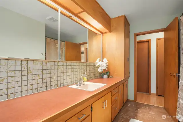 Original Naugahyde counter, backsplash, and classic MCM light detail in the main floor full bath.