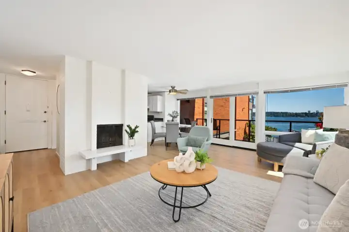 Spacious living area with a cozy fireplace, private balcony access, and walls of windows overlooking Lake Washington.