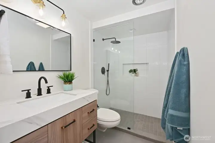 Stylish, fully renovated primary ensuite featuring a glass enclosed shower and designer details.
