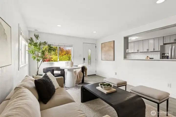 Sun-filled living area at 4612 N 21st St, Tacoma, WA — featuring wide-plank flooring, modern neutral design, open sightlines to the updated kitchen, large picture window with colorful seasonal views, and a cozy dining nook. This North Tacoma home offers a bright, welcoming layout perfect for everyday living and entertaining in a highly desirable neighborhood.