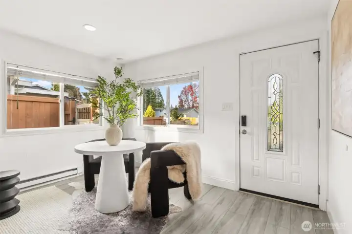 Bright dining nook at 4612 N 21st St, Tacoma, WA — featuring large corner windows with neighborhood views, modern flooring, stylish décor, and a welcoming front entry with decorative glass door. This updated North Tacoma home offers a light-filled, cozy space perfect for morning coffee, work-from-home, or intimate dining.
