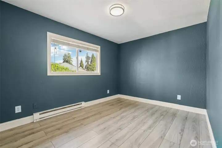 Freshly updated bedroom at 4612 N 21st St, Tacoma, WA — featuring wide-plank wood-look flooring, modern paint tones, crisp white trim, and ample natural light from the adjacent hallway. This versatile North Tacoma room is perfect for use as a bedroom, home office, nursery, or creative space.