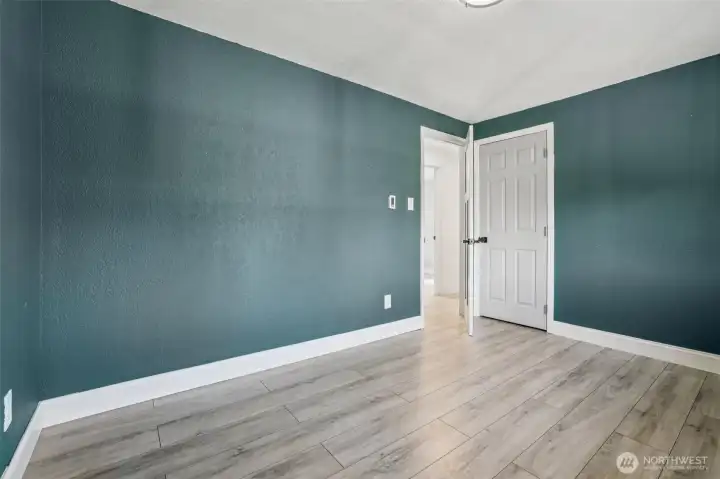Freshly updated bedroom at 4612 N 21st St, Tacoma, WA — featuring wide-plank wood-look flooring, modern paint tones, crisp white trim, and ample natural light from the adjacent hallway. This versatile North Tacoma room is perfect for use as a bedroom, home office, nursery, or creative space.