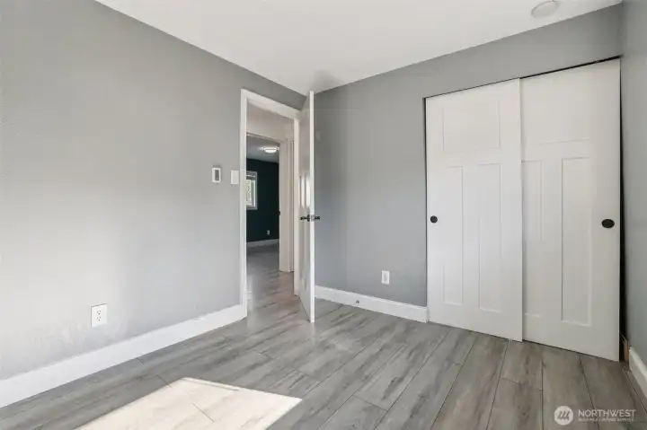 Updated bedroom at 4612 N 21st St, Tacoma, WA — featuring modern gray paint, wide-plank wood-look flooring, white paneled closet doors, and clean trim. This North Tacoma home offers a refreshed, move-in-ready bedroom ideal for sleeping, working from home, or versatile use.