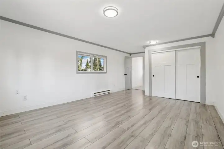 Spacious primary bedroom at 4612 N 21st St, Tacoma, WA — virtually staged to showcase its generous layout, wide-plank flooring, large windows with natural light, and flexible space for a sitting area or home office. This North Tacoma retreat offers comfort, privacy, and room to personalize with modern finishes throughout.
