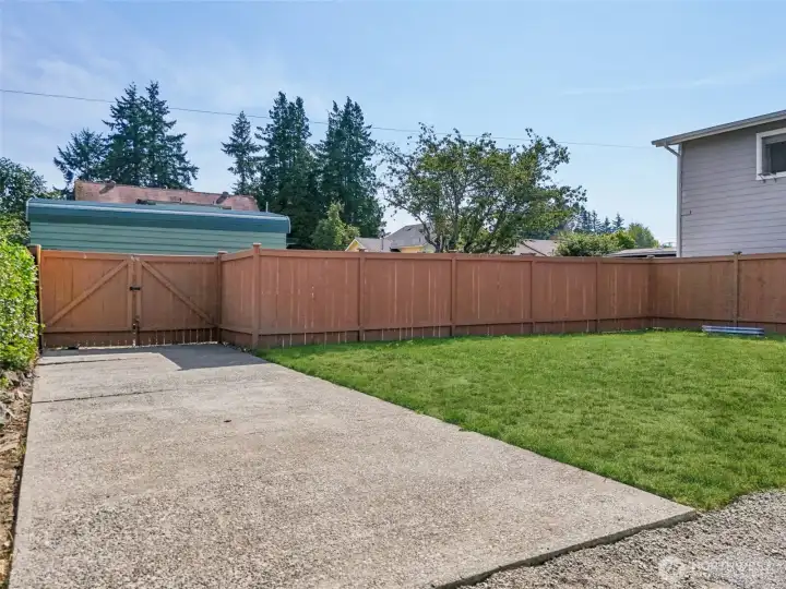 Fully fenced backyard at 4612 N 21st St, Tacoma, WA — featuring a large grassy lawn, double gate access for parking or recreational vehicles, and a private, secure space ideal for pets, play, gardening, or outdoor projects. This North Tacoma yard offers flexibility, privacy, and room to customize. NO HOA!