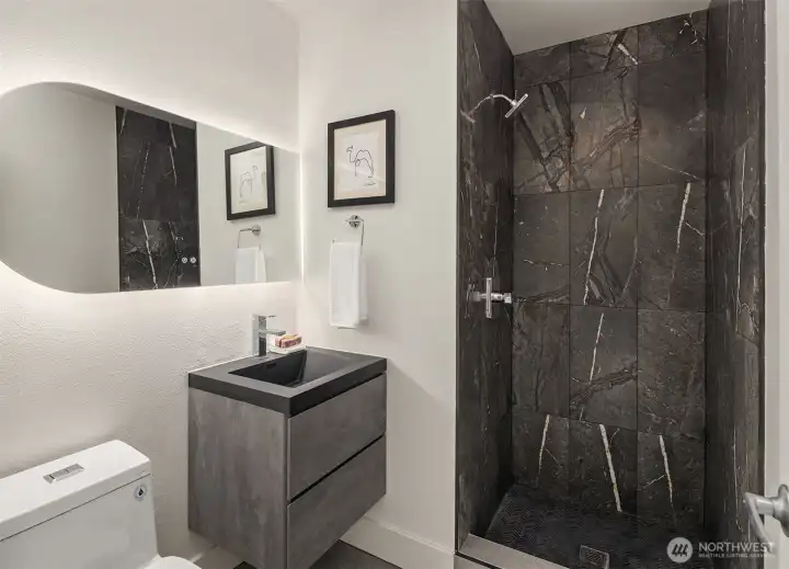 Hall bathroom with large shower stall and natural stone tile