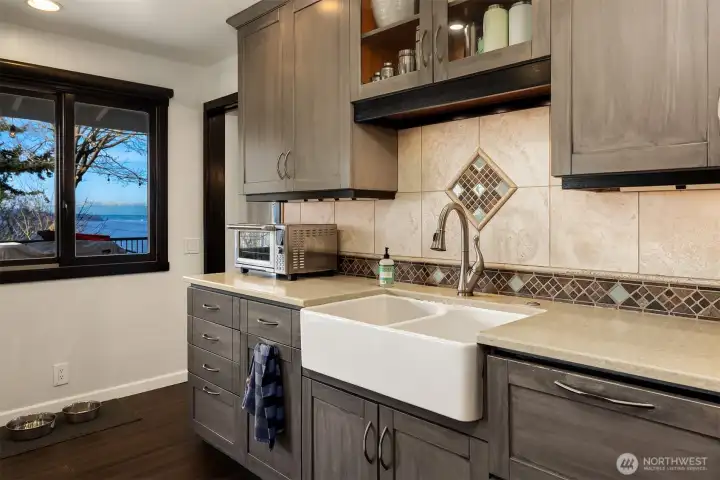 This welcoming kitchen offers a large farmhouse style sink with a deep apron front becoming both a functional workhorse and beautiful focal point.