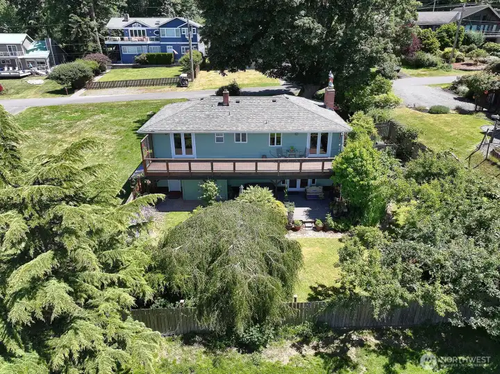 A view of the backyard with mature landscaping that fosters privacy and the expansive cedar deck built in 2021.