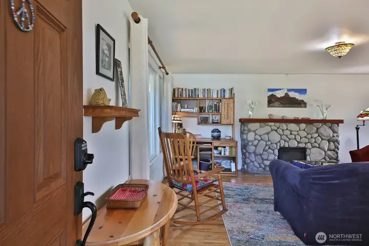 Let's go inside. Here is the front entrance of the home looking into the living room with oak floors and stone fireplace.