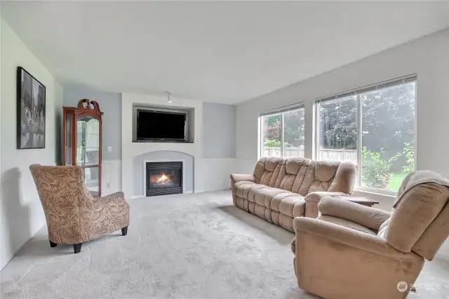 Large family room with gas fireplace & 2 big picture windows looking out to the private  backyard