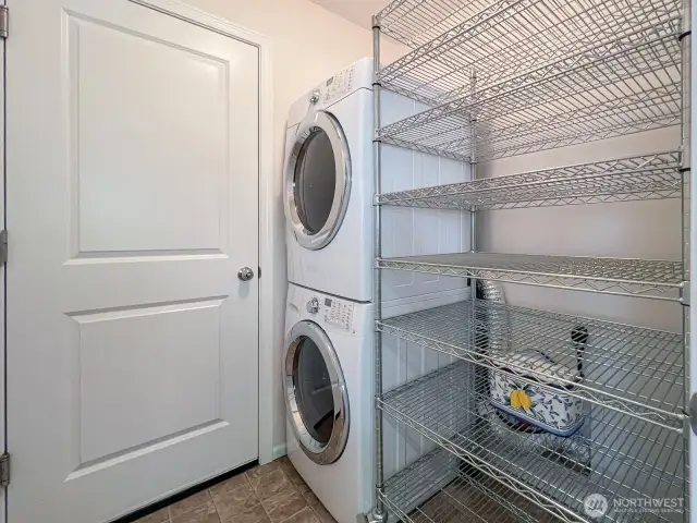 A bright laundry room is conveniently located off the kitchen- thoughtfully stacked configuration with custom ordered shelving unit for storing and organizing all kinds of household staples. Also situated next to the garage for easy unloading from grocery and shopping.  See also seller's custom designed pantry- modeled after Julia Child's own storage space (between kitchen and powder room)