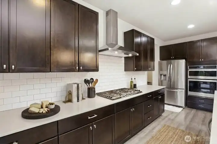 Gas range, subway tile backsplash, overhead fan hood. (digitally staged)