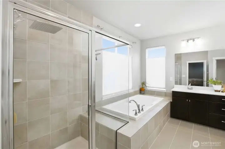 Primary bath ensuite: ceramic tile floors and handy bench in the spacious shower.
