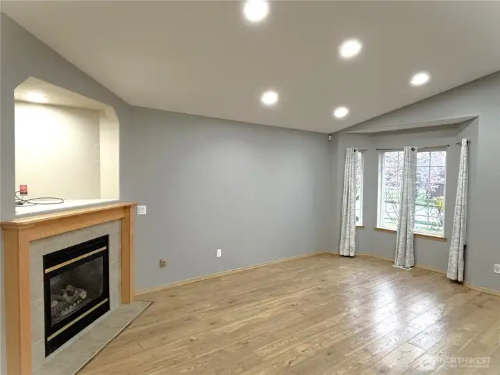 Living room with front windows, theater lights, gas fireplace, entertainment alcove, vinyl wood plank flooring.