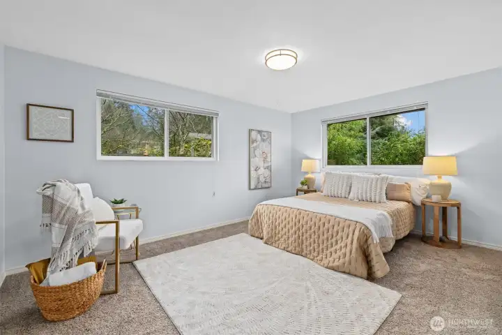 Spacious primary bedroom with large windows, abundant natural light, and serene views