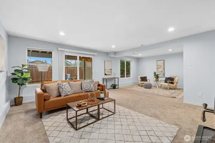 Large lower-level family room with plush carpet, recessed lighting, and sliding door access to the covered patio and backyard.