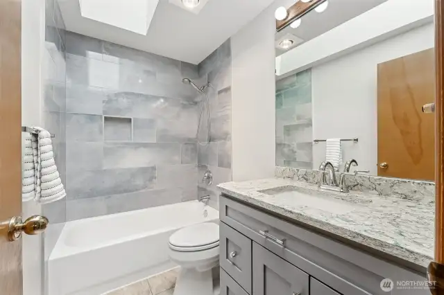 Full bath with an updated quartz countertop and tub/shower combo.