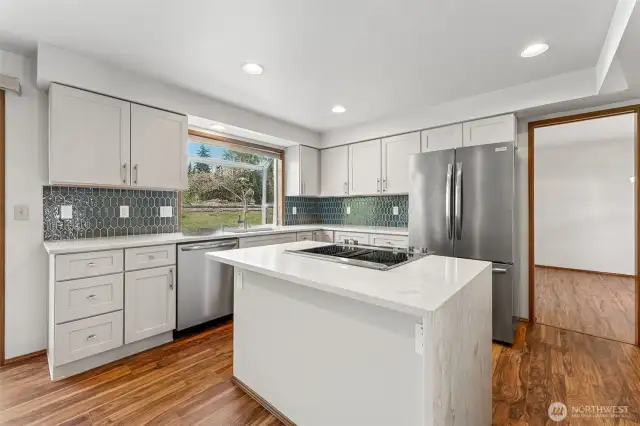 Fully remodeled chef's kitchen with quartz countertops and a center island with cooktop.