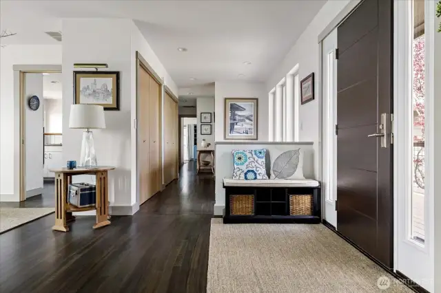 From the entry, looking down the hall toward the half bath and primary suite. At left in photo is the dining room and entry to the kitchen.