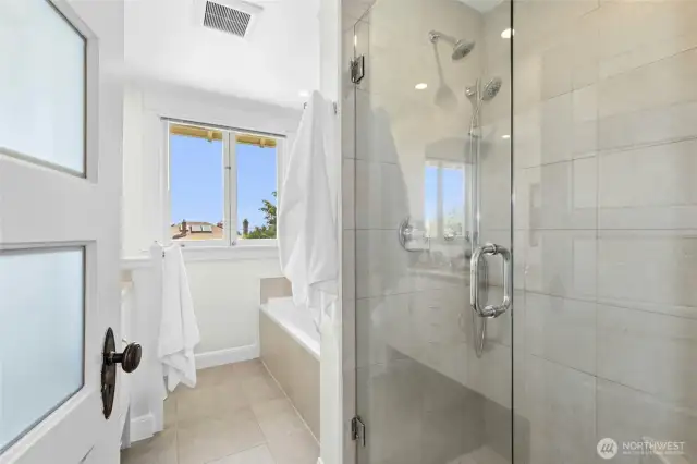 The shared hallway bathroom. Features a walk-in shower as well as a soaking tub and double sink vanity.