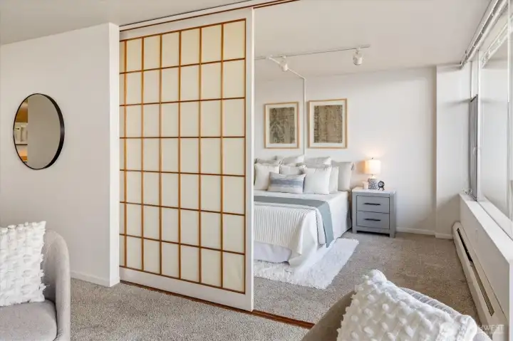 Clever in creating open space, the screen pulls aside to reveal a spacious bedroom.