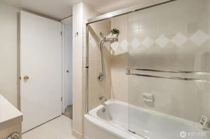 The bathroom features a soaking tub with glass sliders and contemporary tile.