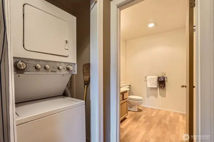 A stacked washer and dryer in the hallway next to the half bath.