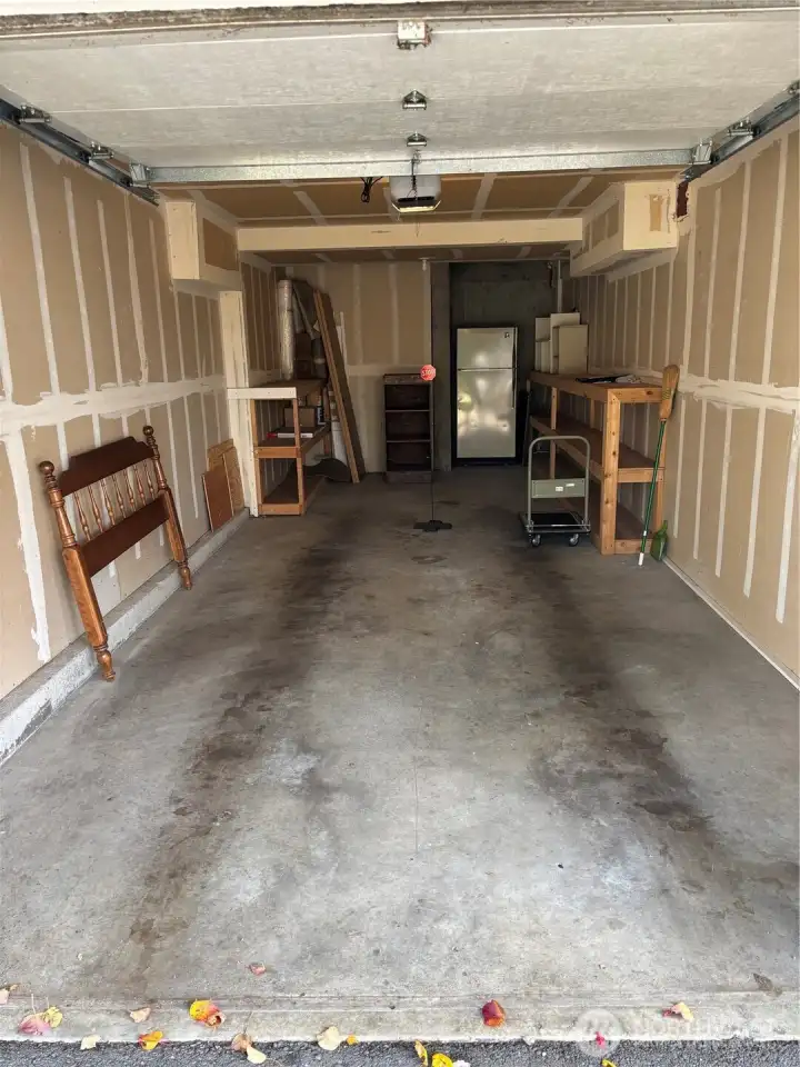 Oversized garage with a rolling cart, shelving and another refrigerator.