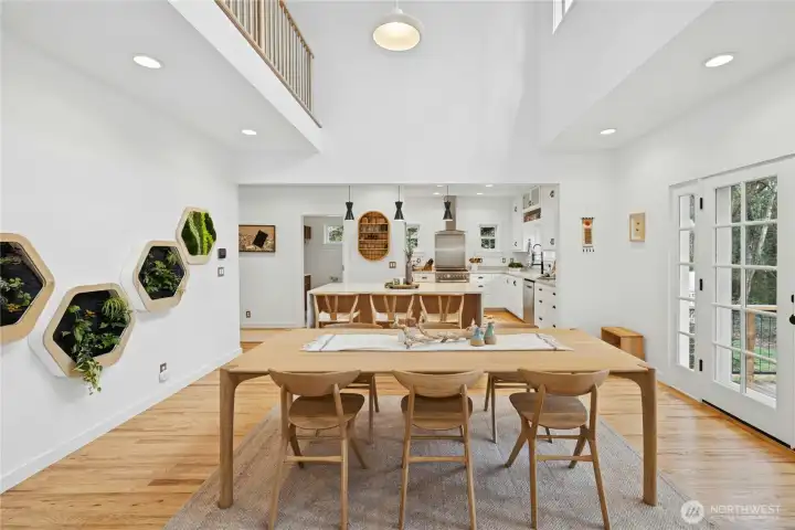 This light-filled dining and kitchen great room showcases the full renovation with soaring ceilings and a designer kitchen anchored by an oversized island. French doors open to the outdoor deck for effortless indoor-outdoor entertaining. Perfect for gatherings after a day on the property.