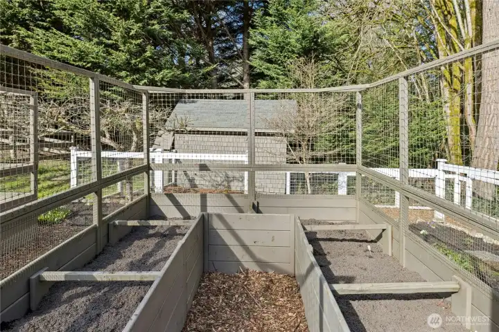 Enclosed garden space features raised beds and protective fencing, creating an ideal setup for cultivating vegetables, herbs, and cut flowers. Designed for productivity and peace of mind, it offers a secure, organized area to grow and harvest right at home.