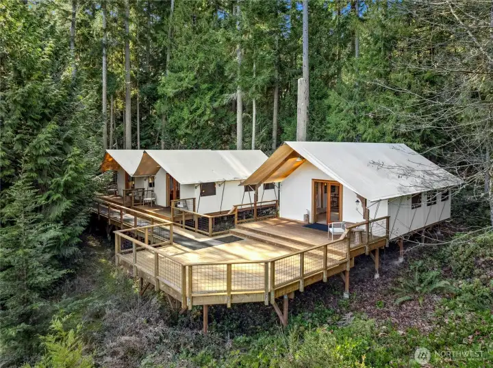 All three Rainier-style safari retreats are set together on an expansive deck, tucked into a peaceful evergreen backdrop for a true getaway feel. They create a unique, resort-like amenity with elevated outlooks over the property.
