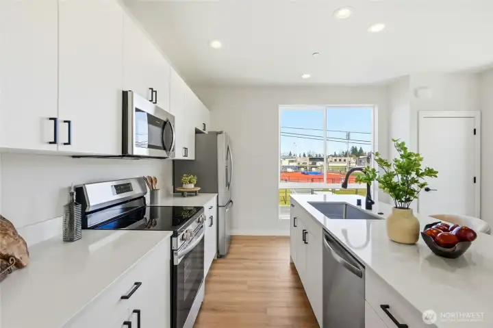 Beautiful quartz counters and stainless appliances make whipping up a meal a breeze. The door to the right is your pantry!