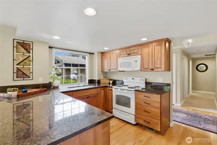 The inviting kitchen features hardwood floors, ample granite countertops and beautiful wooden cabinetry, offering both warmth and functionality.