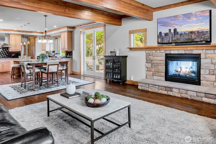 The great room flows seamlessly into the kitchen and dining areas, anchored by a stone fireplace that adds texture and warmth.
