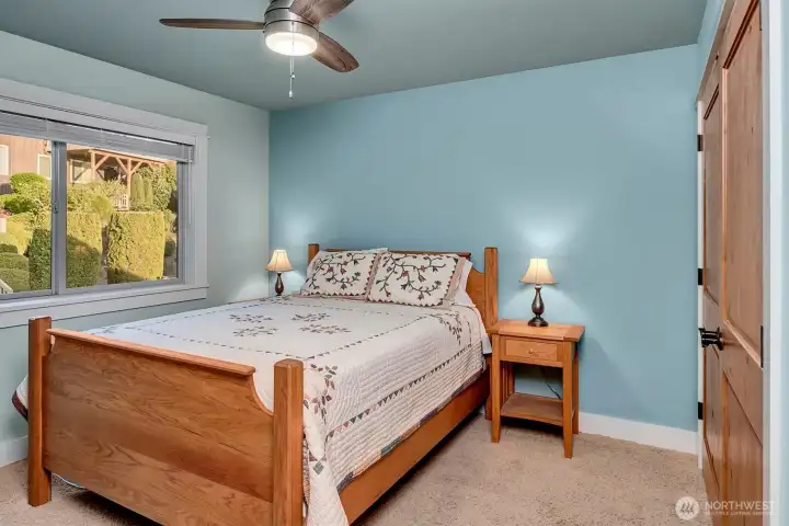 One of three generously sized secondary bedrooms, this space feels both comfortable and well-designed. Soft natural light, wood-wrapped windows, and beautiful double wood doors add warmth and character.