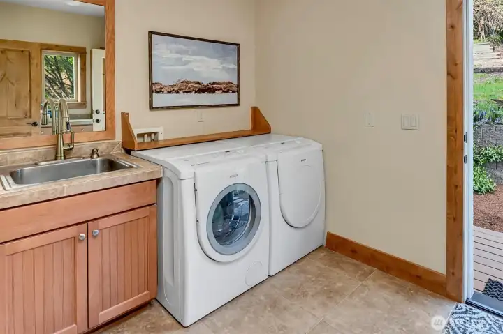 A thoughtfully designed laundry room that makes everyday tasks easier. This spacious area features built-in cabinetry for excellent storage, keeping within reach. A utility sink adds functionality, while the exterior door provides direct access to the backyard-perfect for coming in from outdoor projects or pets.