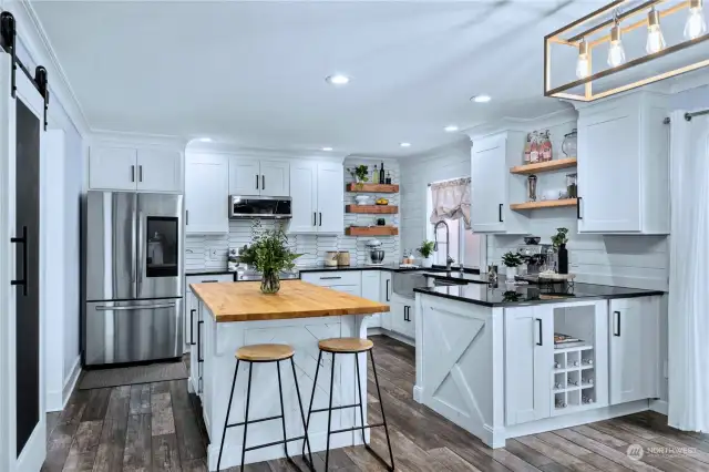 This kitchen is the biggest wow factor for downstairs, fully remodeled with custom details throughout. Reclaimed wood shelves, shiplap, picket style full height tile backsplash, custom ceiling height cabinets and an accent island with bar seating!