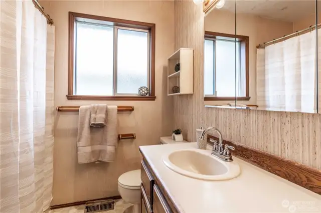 Your classic full bathroom offers warm wood accents, ample storage, and extended countertop space.