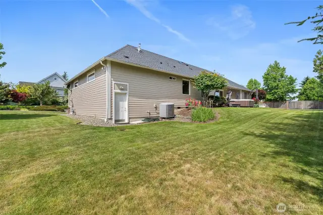 Side backyard with door leading from 3 garage and you can see the large heat pump for heating and cooling.