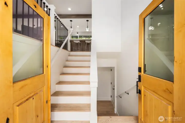 Step inside to a light-filled entry with warm wood accents, fresh paint, and an open staircase leading to stylishly updated living spaces.