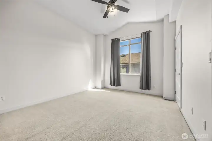 Primary bedroom with vaulted ceilings and ceiling fan