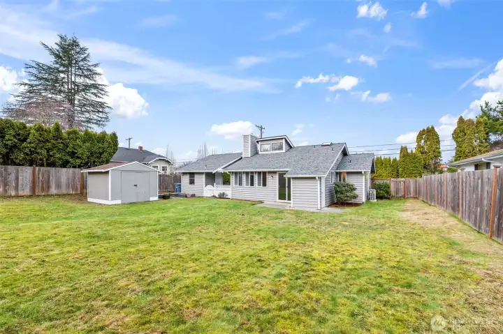 Back of the home with storage shed and back yard
