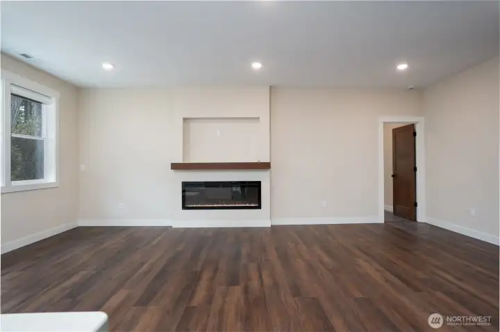 Living area of the great room with electric fireplace and wired TV alcove above.