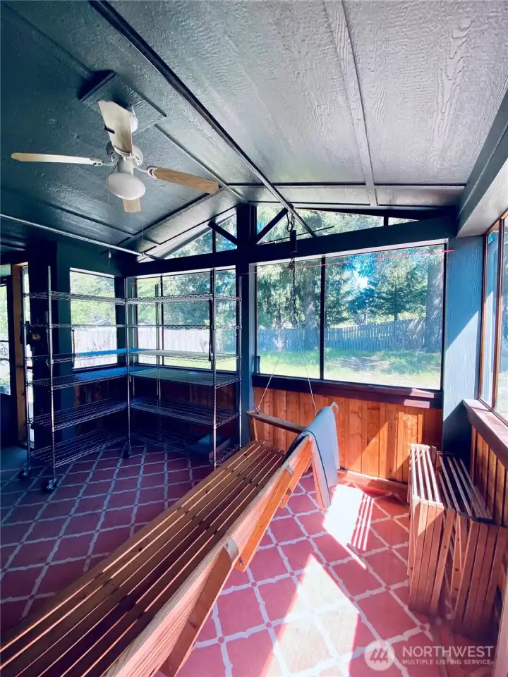 EnclosedCottage porch space with vaulted ceiling, ceiling fan, and porch swing