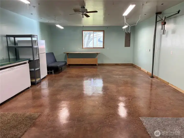 Garage bay number one with engine stained concrete floors, engine hoist, ceiling fan, and electric shop heaters.