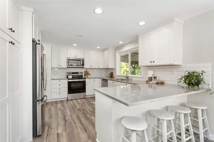 Large eat-in peninsula with quartz counters and full tile backsplash