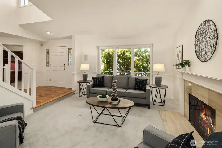 The Front Living Room off the entry way features a gas log fireplace, large garden windows, fresh paint  and new carpeting