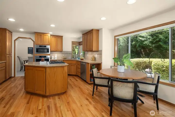 Center Island with Gas Cooktop & Down Draft Vent, breakfast nook area, and refinished hardwood floors