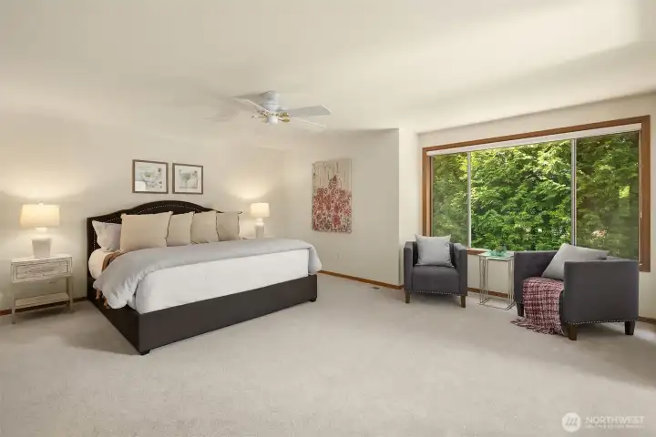 A spacious primary bedroom suite with sitting area & views of the backyard
